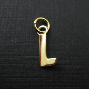 May include: Gold-colored metal charm in the shape of the letter L. The charm has a loop at the top for attaching to a necklace or bracelet.