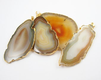 May include: Three agate slices with gold trim, each with a different pattern of brown, white, and orange bands. The slices are arranged in a semi-circle on a white background.