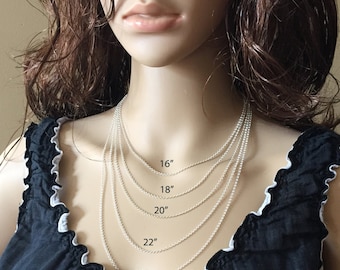 May include: A silver chain necklace in five different lengths: 16 inches, 18 inches, 20 inches, 22 inches, and 24 inches. The necklace is shown on a mannequin wearing a black top.