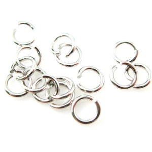 May include: A close-up of a pile of silver jump rings. The rings are small and round, and they are perfect for jewelry making.