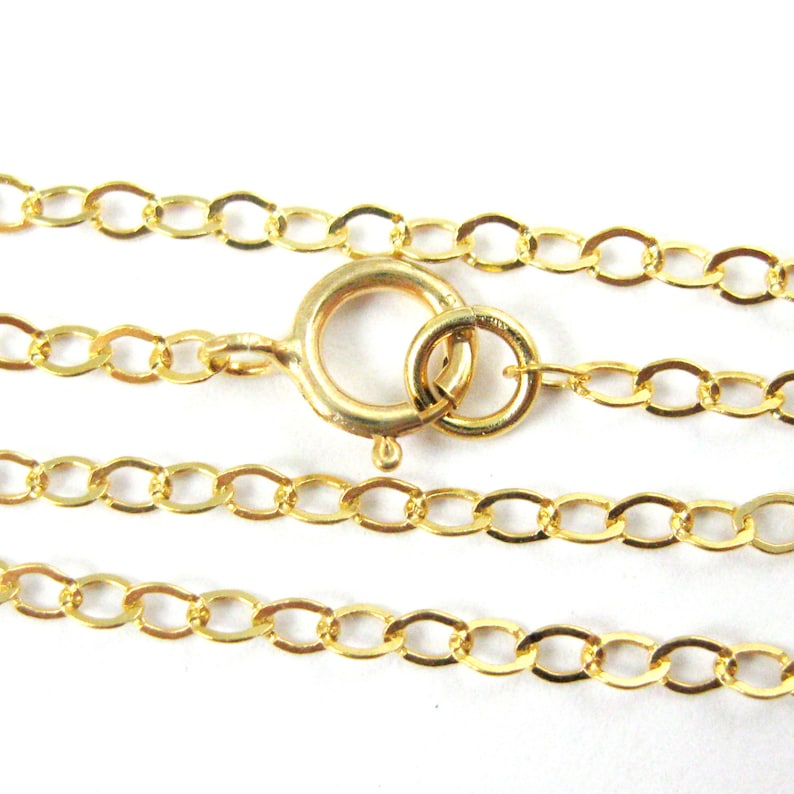 May include: A gold chain necklace with a lobster clasp closure. The chain is made of oval links.