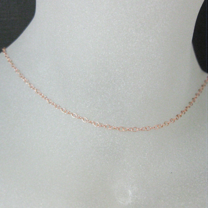 May include: A delicate rose gold chain necklace. The chain is made of small, linked circles.
