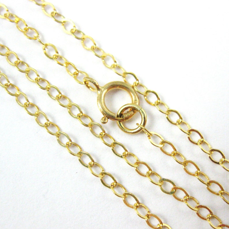 May include: A gold chain necklace with a lobster clasp. The chain is made of oval links.