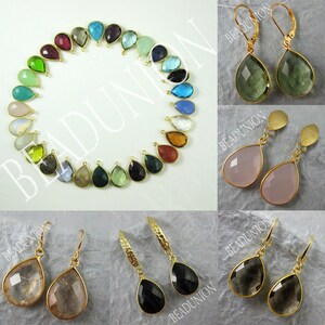 May include: Assortment of gemstone teardrop earrings with gold-tone settings. The earrings feature a variety of colors, including green, blue, pink, and black. The earrings are displayed on a white background.