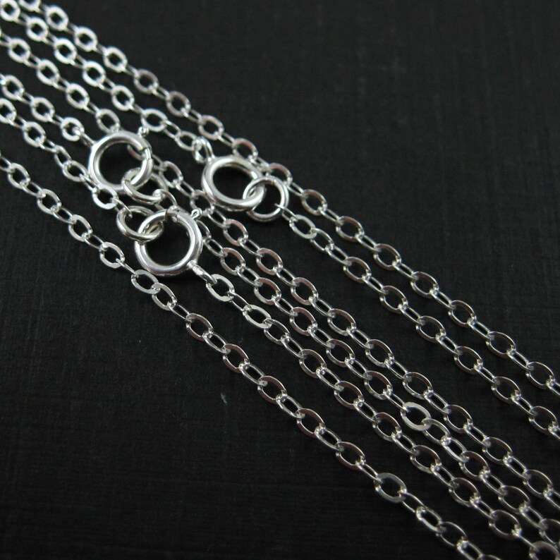 May include: Five silver chain necklaces of varying lengths, all with a classic oval link design.
