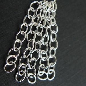 May include: A silver chain with multiple strands of small, linked circles.