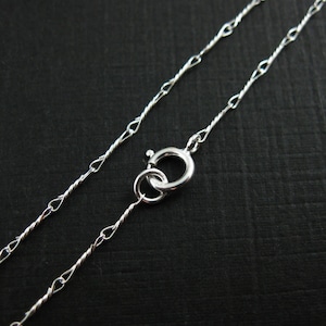 May include: A silver chain necklace with a twisted design and a lobster clasp.