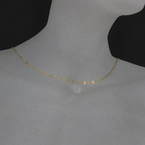 May include: A simple gold chain necklace on a mannequin.