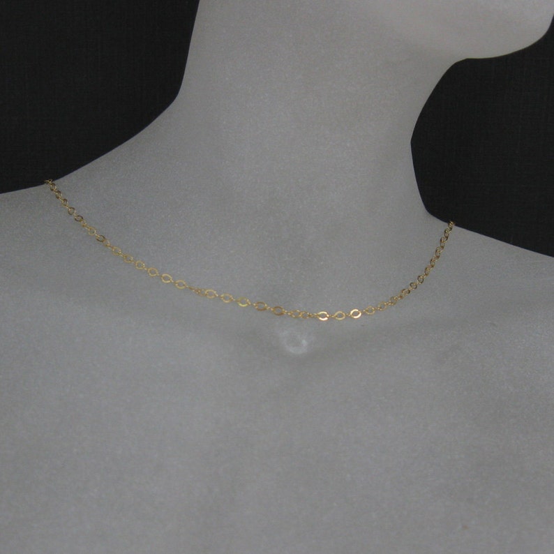 May include: A simple gold chain necklace on a mannequin.