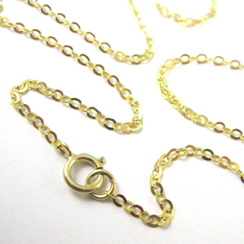 May include: A gold chain necklace with a lobster clasp closure. The chain is made of small, oval-shaped links.