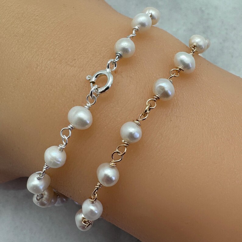 Puede incluir: Una delicada pulsera con perlas blancas ensartadas en alambre de plata y oro. La pulsera tiene un cierre plateado y est&aacute; dise&ntilde;ada para usarse en la mu&ntilde;eca. Las perlas son redondas y est&aacute;n espaciadas uniformemente, creando un aspecto cl&aacute;sico y elegante.