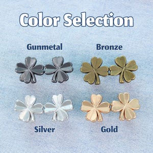 Może przedstawiać: Obraz przedstawia cztery pary metalowych guzik&oacute;w w kształcie koniczyny w kolorze grafitowym, brązowym, srebrnym i złotym. U g&oacute;ry znajduje się napis "Color Selection". Guziki są wyświetlane na jasnoniebieskim tle z dżinsu.