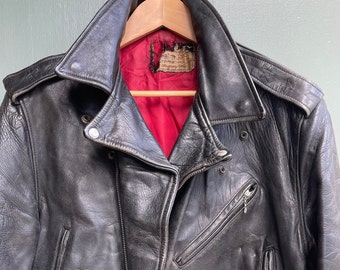 May include: A black leather motorcycle jacket with a red lining and a belt. The jacket has a zipper closure and multiple pockets.