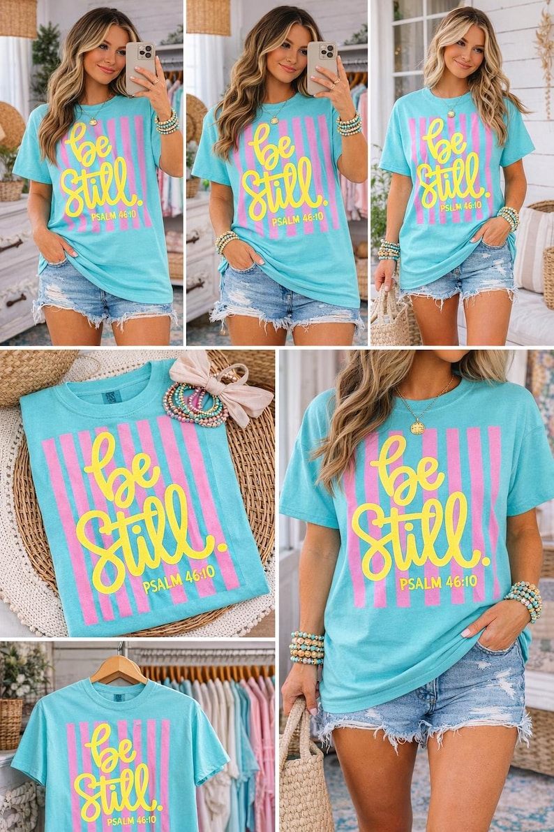 May include: A light blue t-shirt with the words "Be Still" in yellow script, set against pink vertical stripes. The text "PSALM 46:10" is below. The shirt is paired with denim shorts.