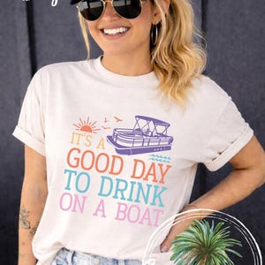 Pu&ograve; includere: T-shirt color avorio con la scritta "IT'S A GOOD DAY TO DRINK ON A BOAT" in lettere colorate. La maglietta presenta una grafica di una barca ed &egrave; abbinata a un berretto bianco con la scritta "LAKE LIFE".