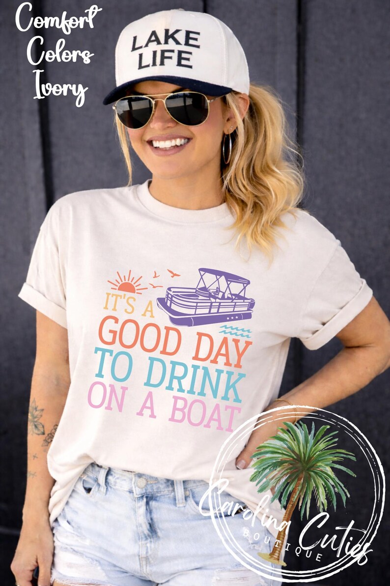 Pu&ograve; includere: T-shirt color avorio con la scritta "IT'S A GOOD DAY TO DRINK ON A BOAT" in lettere colorate. La maglietta presenta una grafica di una barca ed &egrave; abbinata a un berretto bianco con la scritta "LAKE LIFE".