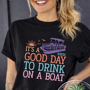 Pu&ograve; includere: T-shirt nero con la scritta "IT'S A GOOD DAY TO DRINK ON A BOAT" in lettere colorate. Il design include una barca, un sole e uccelli. La maglietta &egrave; in stile comfort colors.