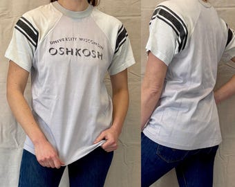 May include: A light blue t-shirt with black and white striped sleeves. The shirt has the text "University Wisconsin Oshkosh" printed on the front.