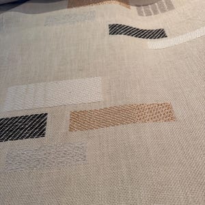 May include: A woven fabric featuring a light beige base with a scattered pattern of rectangular shapes. The rectangles are embroidered in metallic copper, silver, white, and black threads, each displaying a distinct textured, diagonal stitch pattern.