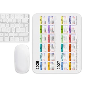 Può includere: Un tappetino per mouse rettangolare bianco con un calendario stampato per gli anni 2026 e 2027. Il calendario mostra i mesi in blocchi colorati con testo nero. Una tastiera e un mouse per computer bianchi sono posizionati sulla sinistra.