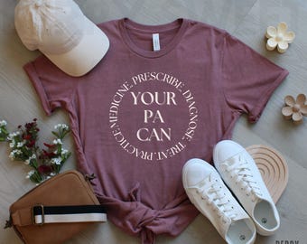 May include: A heather mauve t-shirt with a white circle graphic that says "Your PA Can" with the words "Prescribe, Diagnose, Treat, Practice, Medicine" around the circle.