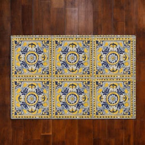 Könnte beinhalten: Sechs quadratische dekorative Fliesen mit einem floralen Design in Gelb, Blau und Weiß. Die Fliesen sind in einem 2x3-Raster auf einer dunklen Holzoberfläche angeordnet. Jede Fliese hat ein zentrales Blumenmotiv, umgeben von Zierornamenten.