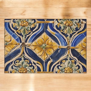 May include: Rectangular decorative tile with a repeating floral pattern. The design features yellow flowers and green leaves set against a blue background. The tile has a black border and is likely ceramic.