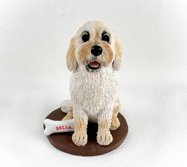 May include: A white ceramic figurine of a dog sitting with a bone that says "BELLA" on it.