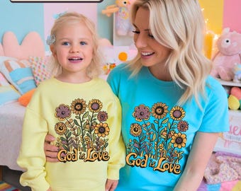 May include: A yellow sweatshirt and a turquoise blue t-shirt with a floral design and the text "God is Love".