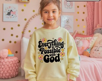 May include: A yellow sweatshirt with a black graphic that says "Everything is Possible with God" surrounded by pink and yellow flowers and stars.