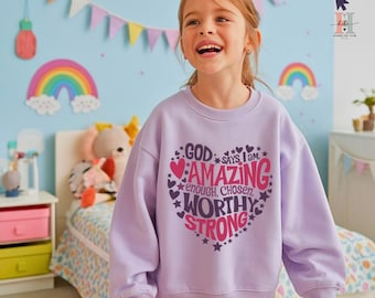 May include: A young girl wearing a lavender sweatshirt with a pink heart graphic that says "God says I am amazing, enough, chosen, worthy, strong".