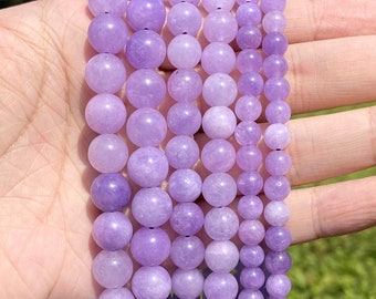 May include: A strand of lavender amethyst beads, with a smooth, polished finish. The beads are round and uniform in size, and they are strung on a clear elastic cord.