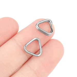 Può includere: Due anelli metallici a forma di triangolo argentati. Gli anelli sono aperti e hanno una finitura liscia.