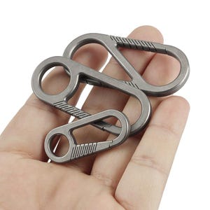 May include: Three silver metal keyrings with a loop design. The keyrings are linked together and have a textured surface.