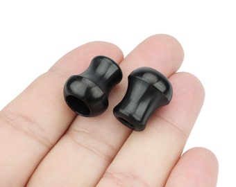 May include: Two black rubber stoppers with a rounded top and a hole in the centre.