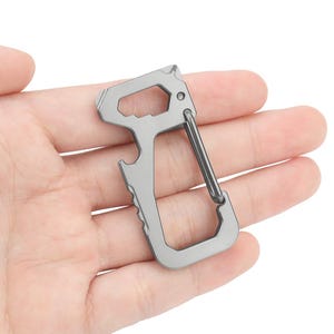 Op de afbeelding: Een zilveren multitool-sleutelhanger met een flesopener, een lus om sleutels aan te bevestigen en een klein gereedschap om items open te wrikken.