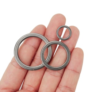 May include: Three silver key rings of different sizes. The rings are made of metal and have a smooth, polished finish.