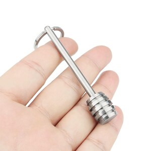 以下が含まれることがあります： キーホルダーが付いたシルバーメタルのハニースプーン。スプーンは長く細いハンドルと丸く溝の入ったヘッドを持っています。
