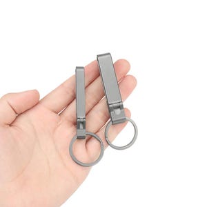 May include: Two silver keychains with a metal ring. The keychains have a flat, rectangular shape with a smooth, metallic finish.