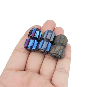 May include: Three metal beads, two are blue and one is brown. The blue beads have a textured surface and the brown bead has a swirling pattern.