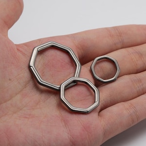May include: Three silver octagonal key rings of different sizes.