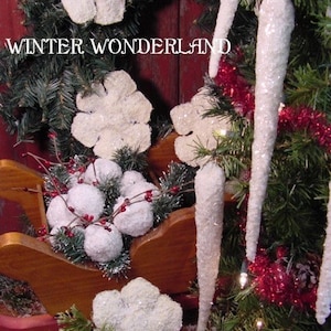 May include: White sparkly snowflake ornaments and icicle ornaments with red and white tinsel on a green pine tree. The text "WINTER WONDERLAND" is visible on a red wooden background.