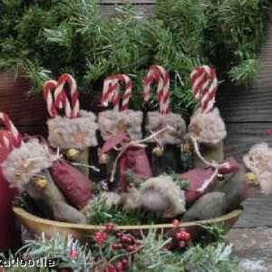 May include: A bowl filled with handmade Christmas ornaments. Each ornament is a small, fabric-covered figure with a candy cane attached. The ornaments are in shades of red, white, and brown.