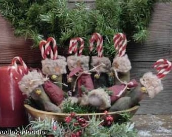 May include: A bowl filled with handmade Christmas ornaments. Each ornament is a small, fabric-covered figure with a candy cane attached. The ornaments are in shades of red, white, and brown.