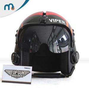 Könnte beinhalten: Schwarzer und roter Top Gun Viper-Pilotenhelm mit Visier. Auf dem Helm steht das Wort "VIPER". Vor dem Helm befindet sich eine Karte mit dem Top Gun Maverick-Logo.