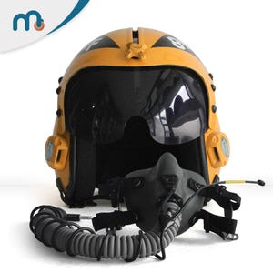 Könnte beinhalten: Ein gelber Pilotenhelm mit schwarzem Visier und schwarzer Sauerstoffmaske. Der Helm hat schwarze Markierungen und einen gewendelten grauen Schlauch. Der Helm ist für die Luftfahrt konzipiert.