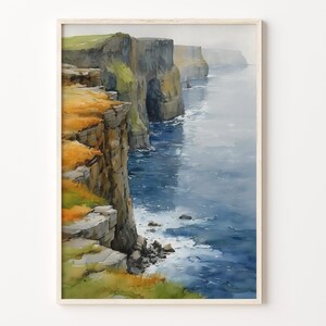 May include: A watercolor painting of steep, rugged coastal cliffs featuring shades of dark gray, brown, and vibrant green grass. The cliffs drop sharply into a deep blue ocean with white sea foam visible at the base, all framed in a light wood border.