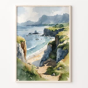 Può includere: Un dipinto ad acquerello di una costa rocciosa con vista su un oceano blu e una spiaggia sabbiosa. Il dipinto presenta un sentiero che conduce alla spiaggia, con erba verde e vegetazione su entrambi i lati.