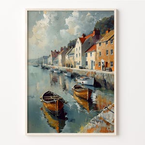 May include: A framed watercolor painting depicts a coastal village scene. Several small boats float in the water, reflecting the buildings and sky. The buildings are a mix of orange, white, and brown, with red-tiled roofs. The sky is cloudy with hints of blue.