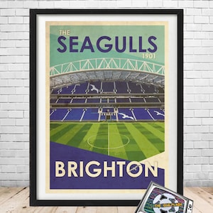 Puede incluir: Un póster de estilo vintage que presenta un estadio de fútbol con un campo verde y asientos azules. El póster tiene el texto "THE SEAGULLS 1901" y "BRIGHTON" en una fuente retro.